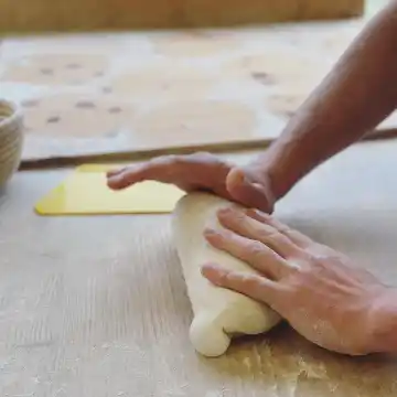un homme pétrissant un pâton de pain